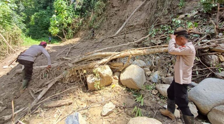 Aparat Polsek Kulawi melewati jalan yang longsor di salahs atu titik yang longsor di Pipikoro. (Foto: Humas Pores Sigi)