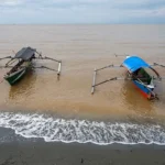 Perahu nelayan tertambat di bibir pantai Tambarana yang berwarno coklat terpapar limbah tambang emas, Rabu (18/6/2025). (bmzIMAGES)