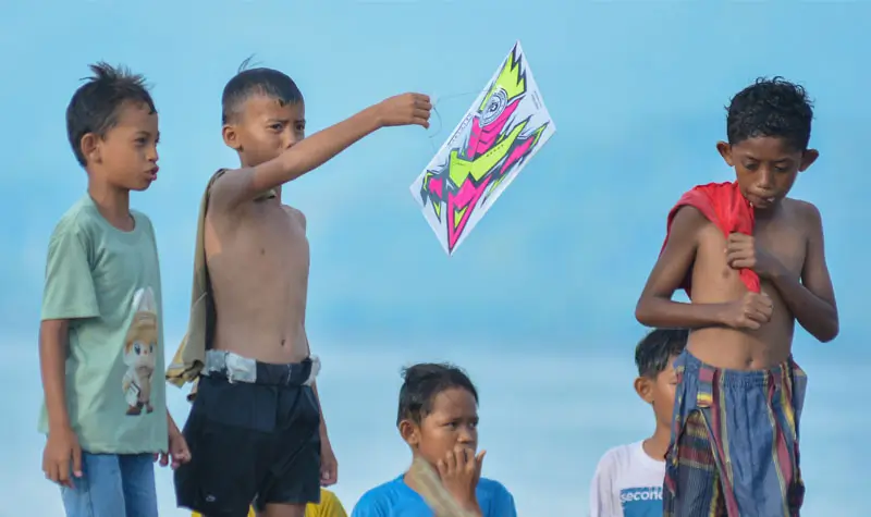 Seorang anak menunjukkan layangan aduan yang berhasil diburu pada Festival Layangan di Dongala, Kamsi (25/9/2025). (© bmzIMAGES/basri Marzuki)